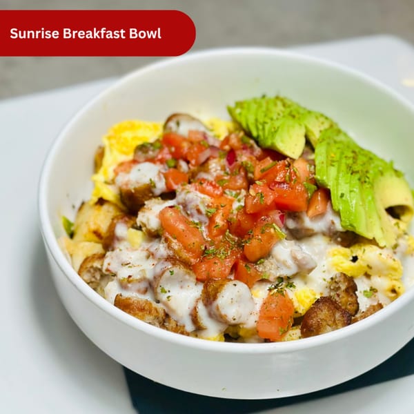 A Sunrise Breakfast Bowl from Mom's Kitchen, with eggs, sausage, gravy, diced tomatoes, and avocado slices.