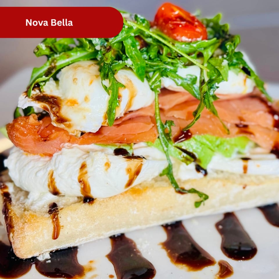 Nova Bella breakfast dish with smoked salmon, burrata, arugula, and cherry tomatoes on a waffle.