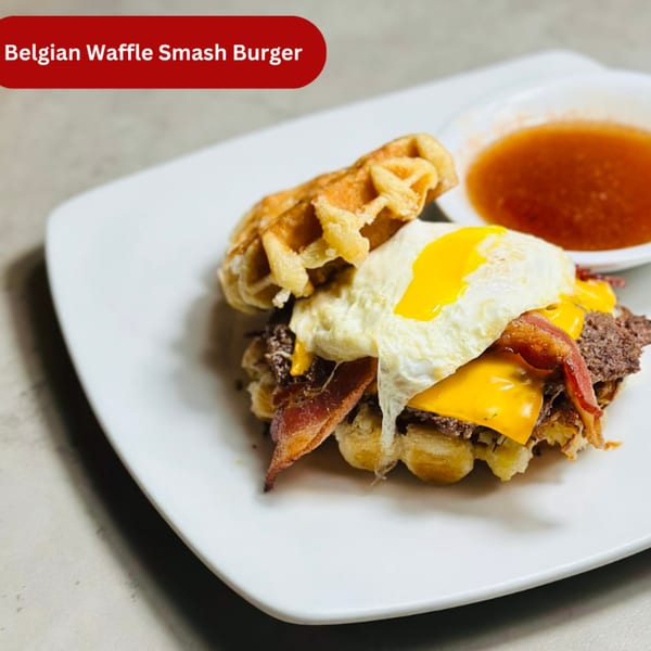 Mom's Kitchen Belgian Waffle Smash Burger with egg, bacon, cheese, and a side of syrup.