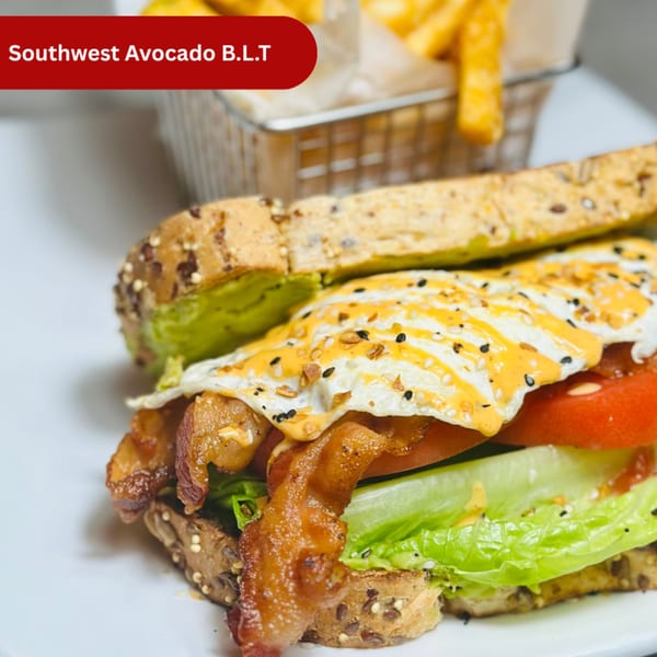 Southwest Avocado B.L.T. sandwich with bacon, lettuce, tomato, avocado, fried egg, and fries.
