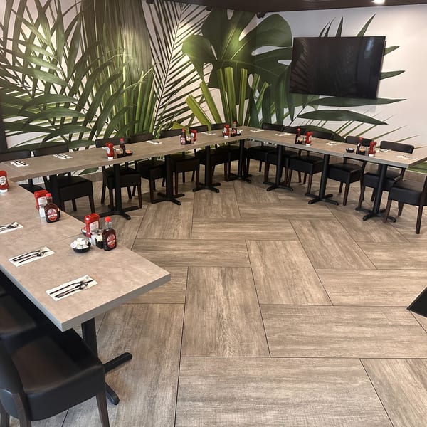 A spacious dining area at Mom's Kitchen with tables arranged in a U-shape, featuring a tropical leaf mural.