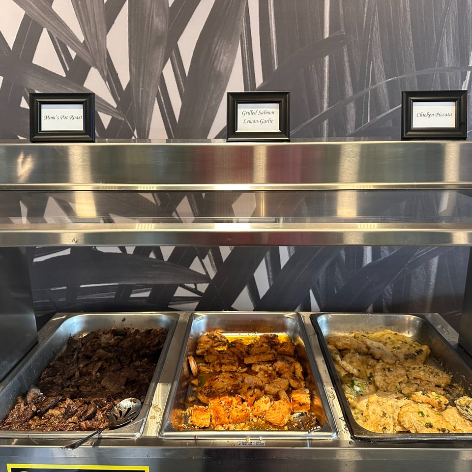 Mom's Kitchen buffet with Mom's Pot Roast, Grilled Salmon, and Chicken Piccata in serving trays.